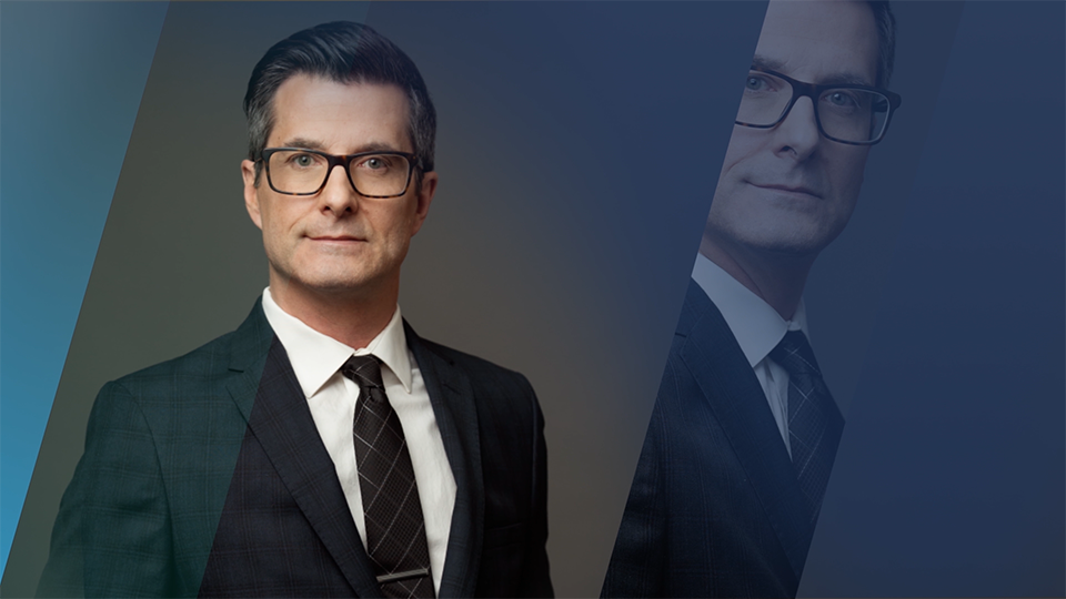 An image of a man in a suit with slices of gradient blues overlaid across the frame.