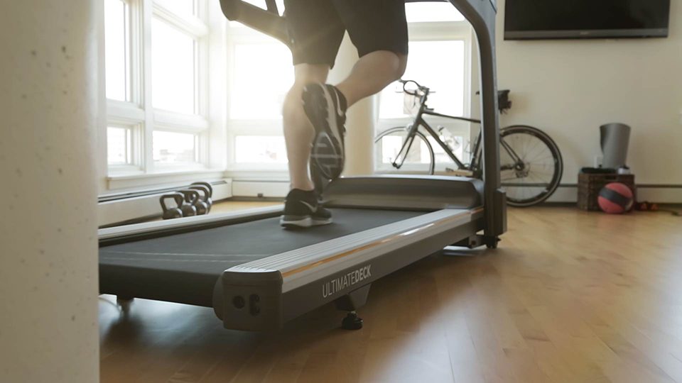 A cropped image of a man's legs running on a treadmill.