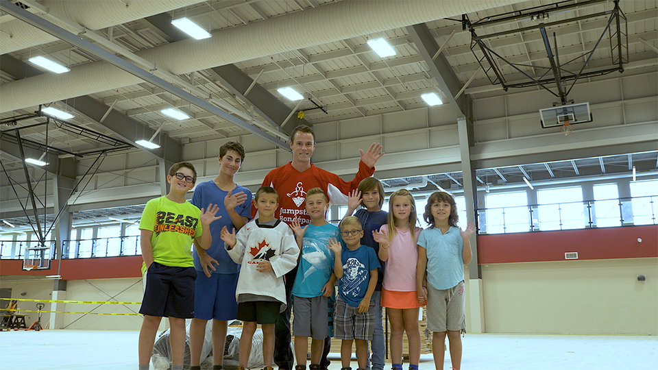 An image of hockey player Jonathan Toews waving with a group of waving children.