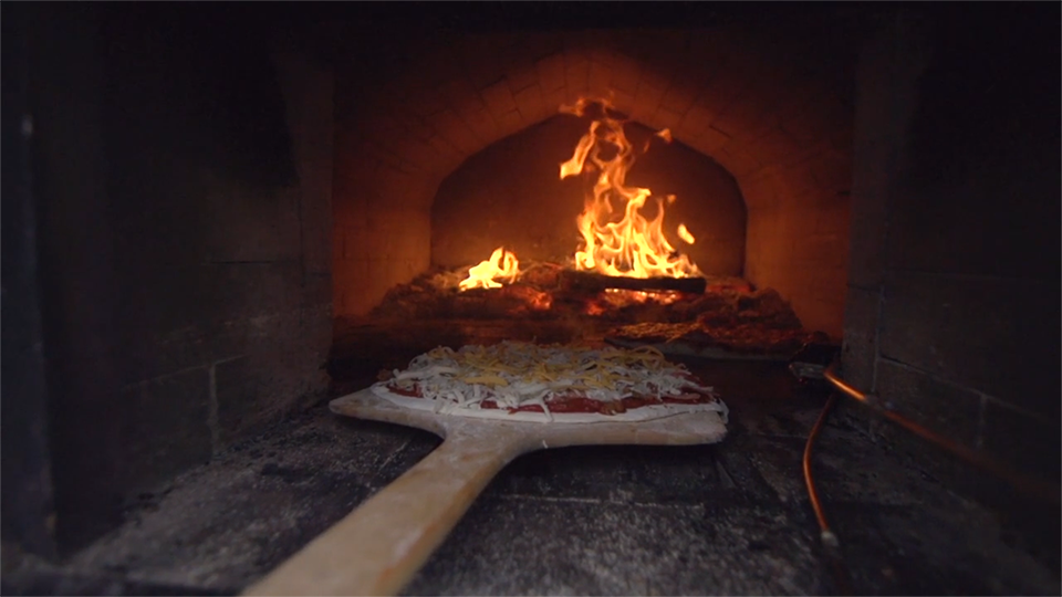 An image of a pizza that is being slide into a pizza oven.
