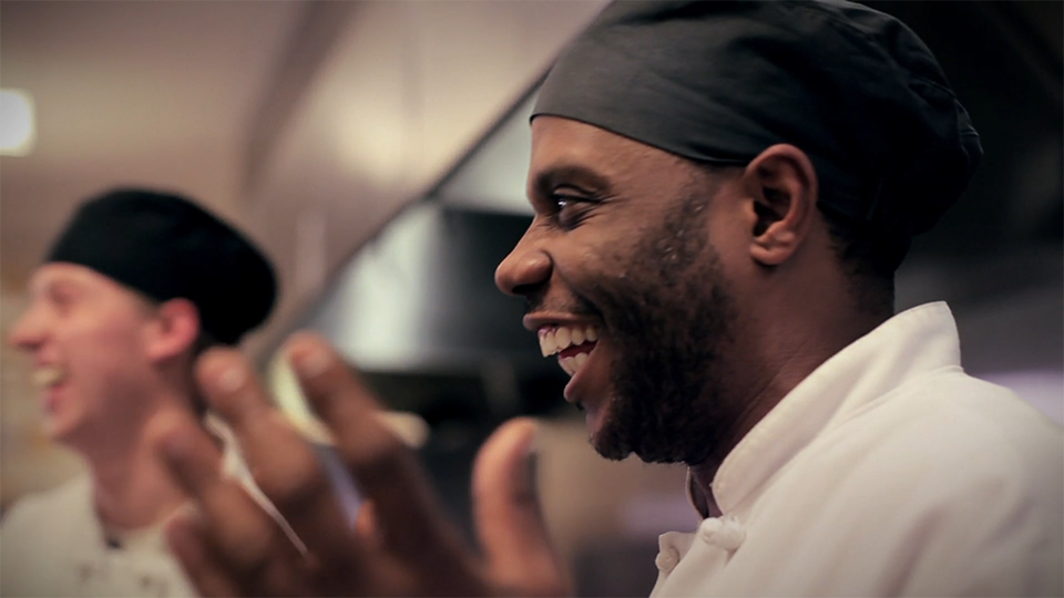 A close up profile image of a man smiling and clapping.
