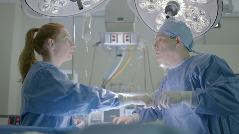 An image of a woman passing a man a scalpel in an operating room.