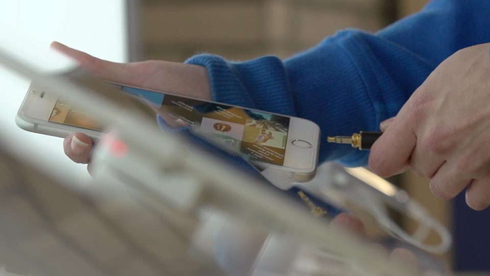 An image of a a person's hands plugging in an iPhone into a cord.