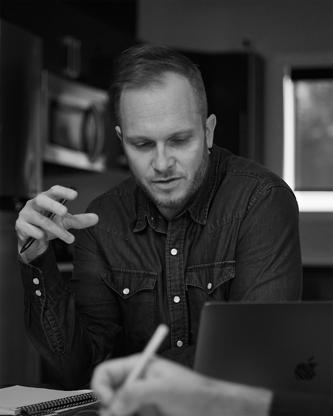 A black and white image of Adam, the principal of Coelement speaking to other team members.
